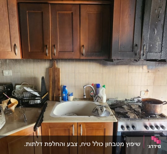 מטבח עם ארונות שרופים ותקרה מפויחת לאחר שריפה